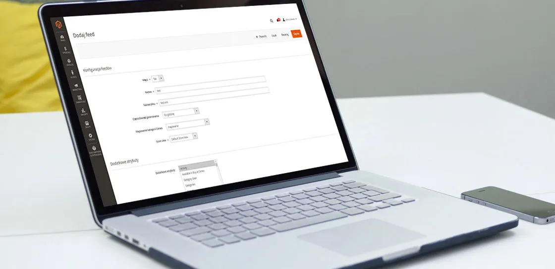 Formularz dodawania feedu w panelu Magento 2 na ekranie laptopa: sekcja Konfiguracja feedu z polami Włącz, Nazwa, Nazwa pliku, Częstotliwość generowania ustawioną na „Co godzinę”, Mapowanie kategorii Ceneo oraz Store view ustawionym na Default Store View, a pod nią sekcja Dodatkowe atrybuty z rozwiniętą listą atrybutów produktu, w której widnieje pozycja „Available in Buy at Ceneo”.