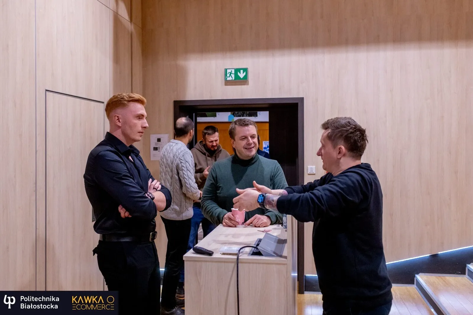 Czterech uczestników rozmawia przy stoliku w kuluarach spotkania Kawka o e‑commerce na Politechnice Białostockiej.